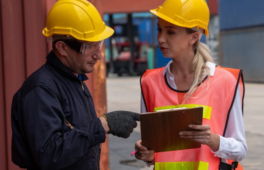 Workers in hardhats speaking in shipping depot - Customs Clearance concept