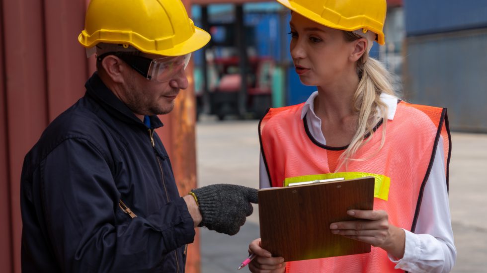 Workers in hardhats speaking in shipping depot - Customs Clearance concept